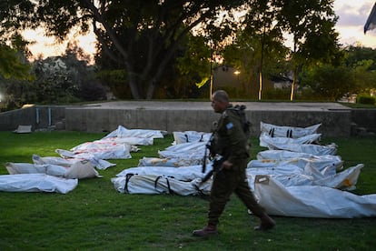 Un soldado israelí camina junto a los cadáveres de más de 20 militantes de Hamás, con la palabra "terrorista" escrita en hebreo, el 11 de octubre de 2023 en el kibutz Beeri, donde decenas de civiles fueron asesinados días antes.