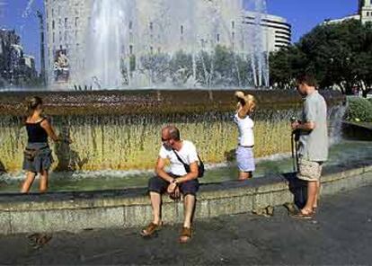 Los barcelonses se refrescan en la fuente de la Plaza de Catalunya.