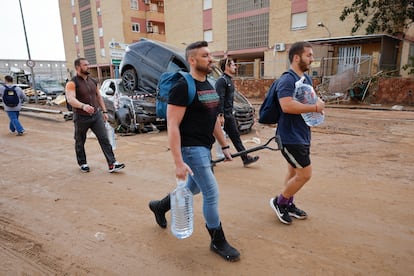 Varios vecinos llevan garrafas de agua en la localidad de Paiporta (Valencia), donde han muerto 40 personas tras el paso de la dana, este jueves. 