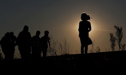 Inmigrantes caminando por las vías del tren al anochecer en Röszke, Hungría.