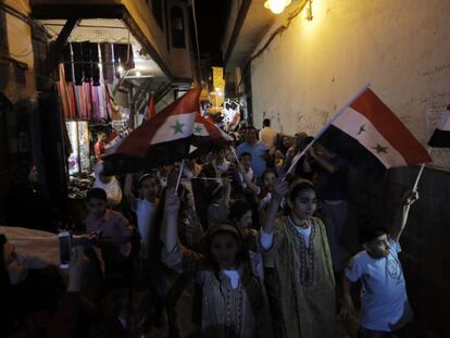 Niños sirios sostienen banderas nacionales en Damasco, el martes 12 de junio de 2018.