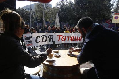 Siete agentes de la Brigada Móvil (Brimo) de los Mossos d'Esquadra han resultado heridos este jueves durante el desalojo de una manifestación de los CDR por la huelga que cortaba la autopista AP-7 en Sant Julià de Ramis (Girona), un tramo que ya ha sido reabierto. En la imagen, dos jóvenes se toman un café en un establecimiento de Terrassa mientras un grupo de activistas independentistas protestan.