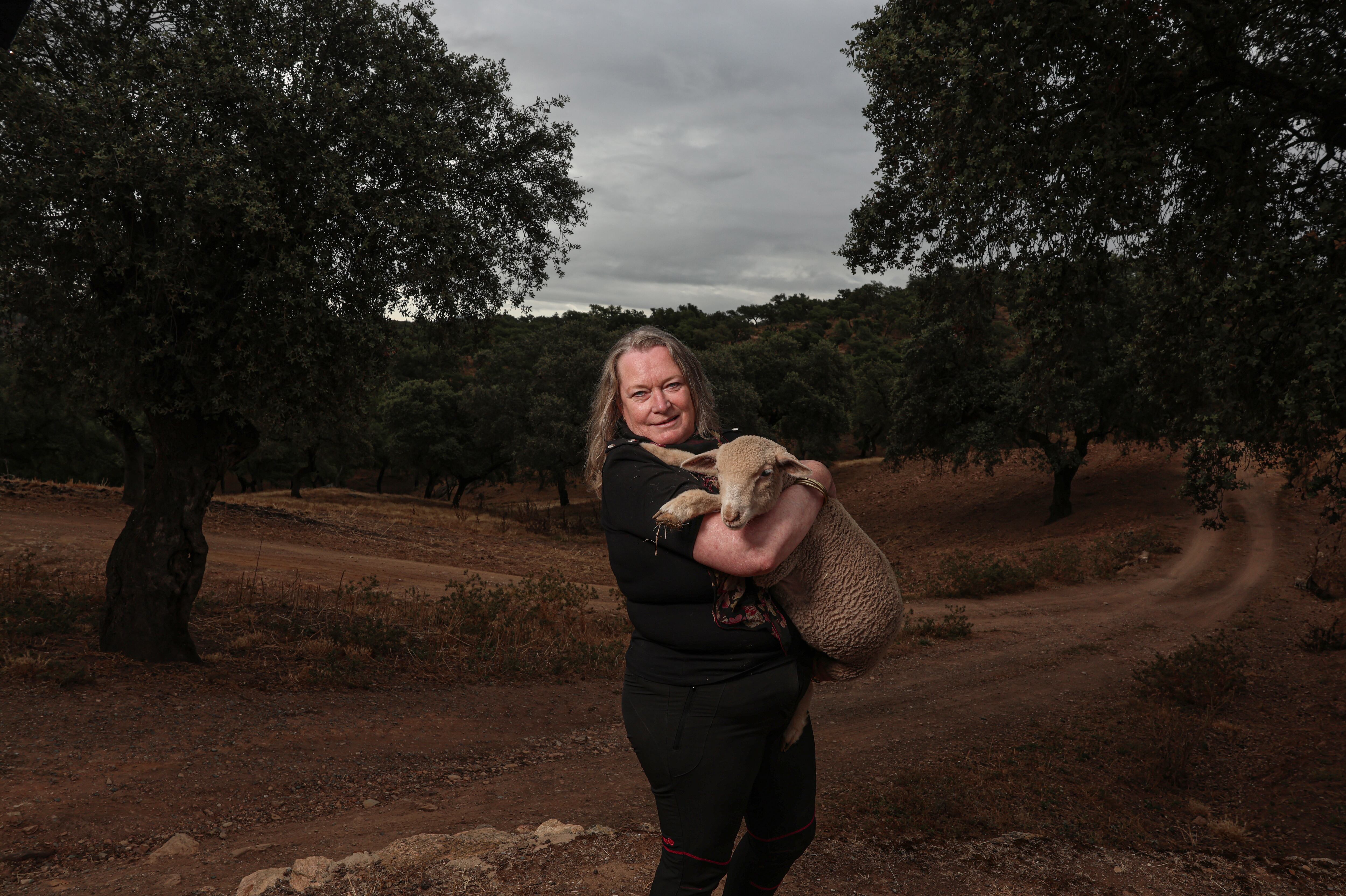 Ernestine Lüdeke sostiene una oveja en su finca de Santa Olalla del Cala (Huelva). 
