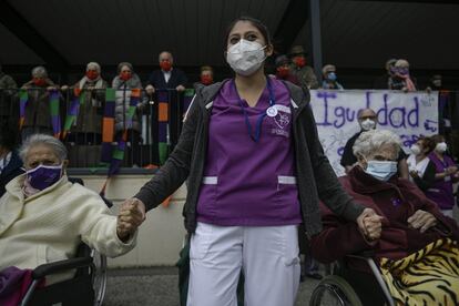 Una trabajadora sanitaria de la residencia de ancianos San Jerónimo da la mano a dos ancianas mientras participan en un acto durante el Día Internacional de la Mujer, en Estella, al norte de Pamplona. En toda España se han celebrado numerosos actos de pequeño tamaño organizados de forma creativa para evitar concentraciones que puedan desencadenar un nuevo pico de contagio del coronavirus.