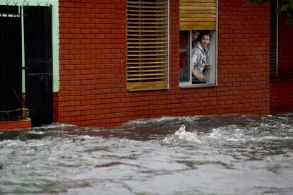 Una pareja mira por la ventana de su casa en una calle inundada en la ciudad argentina de Buenos Aires.