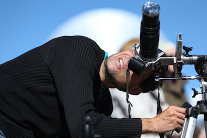 Un hombre observa el sol a través de su cámara fotográfica horas antes de que comience el eclipse solar total.