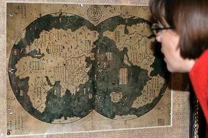 Una mujer examina atentamente el mapa que muestra las costas de medio mundo, y que supuestamente alcanzó en el siglo XV el navegante chino Zheng He. Entre ellas, la de América, a la que habría arribado siete décadas antes que Colón.