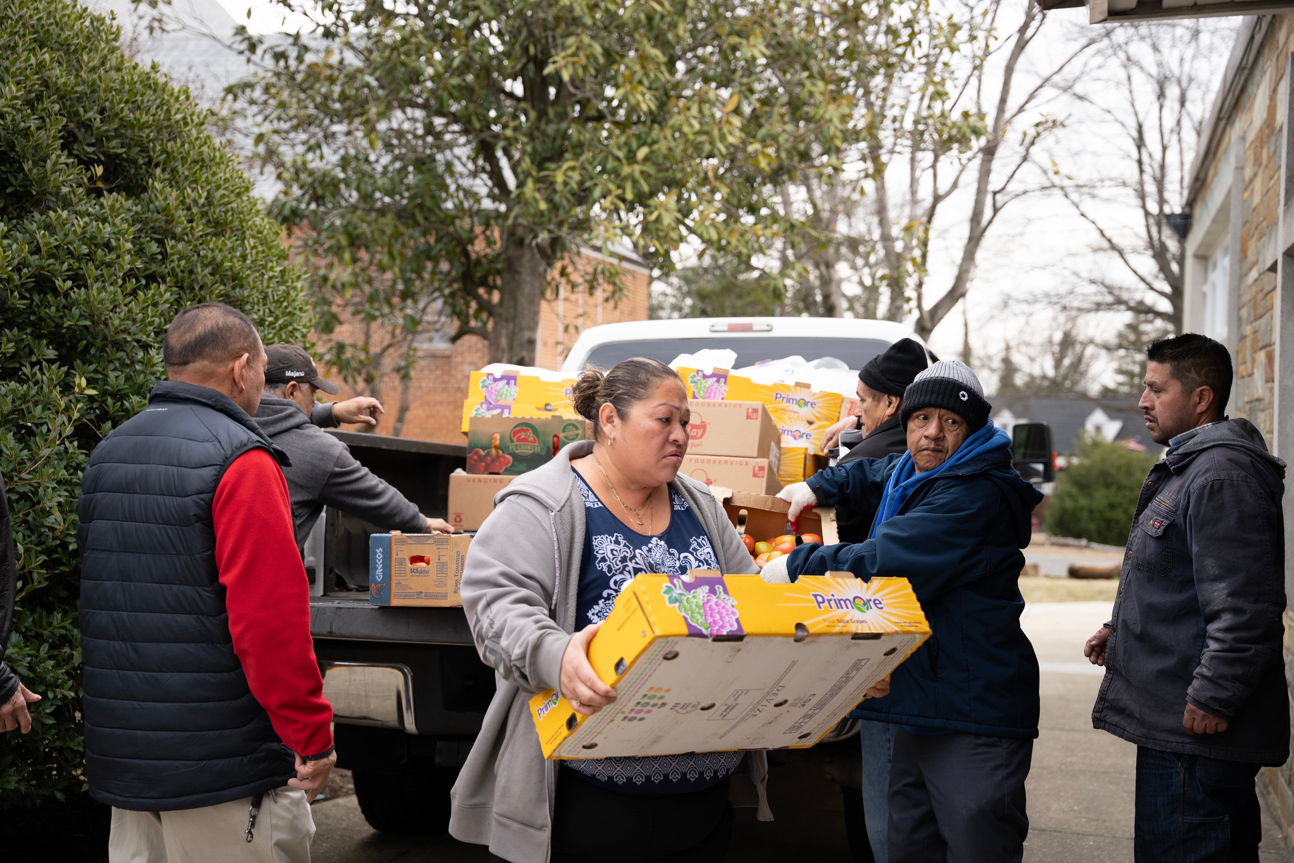 Migrantes voluntarios ayudan al padre Vidal a descargar un camión lleno de productos donados por Food for Justice. 