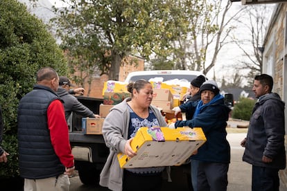 Migrantes voluntarios ayudan al padre Vidal a descargar un camión lleno de productos donados por Food for Justice.