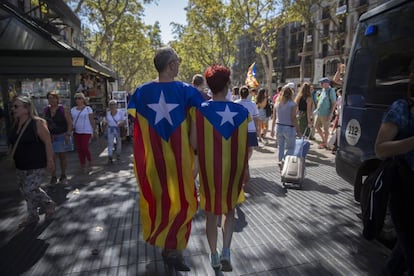 Una pareja ataviada con esteladas pasean por Las Ramblas.