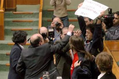 El vicepresidente del Parlamento vasco, Carmelo Barrio (izquierda), intenta quitar un cartel a un joven radical &#39;abertzale&#39;.