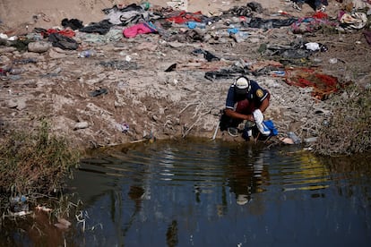 Un migrante lava ropa en el río cerca de la frontera en Ciudad Juárez.