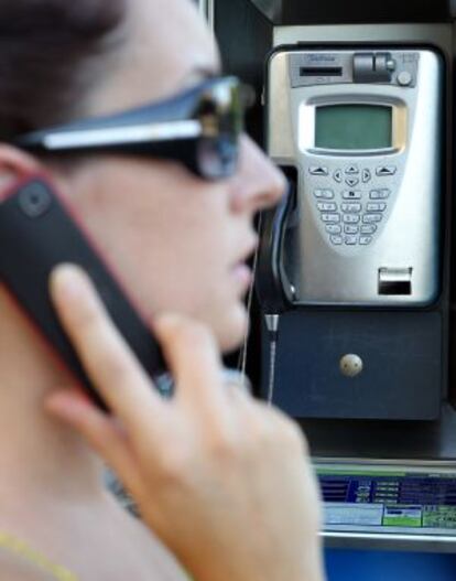 Una mujer habla junto a una cabina de Telefónica