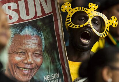 Un sudafricano canta y muestra un retrato del expresidente Nelson Mandela en el estadio FNB de Soweto durante el servicio religioso oficial en memoria del expresidente.