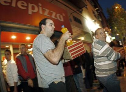 Varios clientes salen de un establecimiento de Telepizza en Madrid.