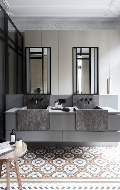 El baño tiene dos lavabos de piedra italiana sobre un mueble con espejos iluminados en los laterales. La grifería es de Dornbracht, y los accesorios, de Decor Walther.