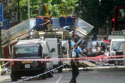 Un operario de los servicios de rescate pasa por delante del autobús destruido por una bomba cerca de Russell Square, en Londres.