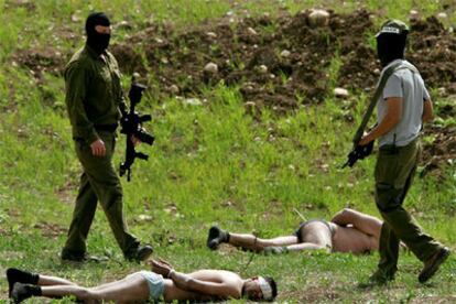 Dos palestinos que viajaban en una camioneta fueron detenidos ayer en Latrun, entre Jerusalén y Tel Aviv, tras una espectacular persecución en la autopista al sospechar los israelíes que llevaban explosivos a bordo. En la foto, dos agentes de las fuerzas especiales vigilan a los detenidos, que se encuentran maniatados y semidesnudos en el suelo.