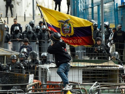 Un manifestante ondea una bandera de Ecuador delante de la Asamblea Nacional rodeada de policía este sábado.