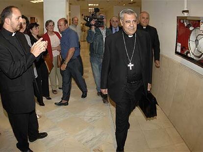 Un sacerdote aplaude al arzobispo de Granada en los pasillos de los juzgados, donde declaró ayer.