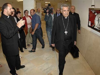 Un sacerdote aplaude al arzobispo de Granada en los pasillos de los juzgados, donde declaró ayer.