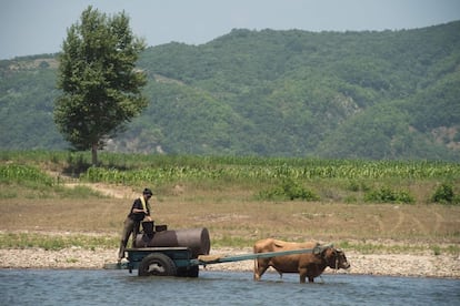 Um norte-coreano abastece um tanque de água às margens do rio Yalu, próximo de Sinuiju, no lado oposto da cidade fronteiriça de Dandong, na China.