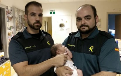 Dos agents amb el bebè trobat en un contenidor subterrani a Mejorada del Campo (Madrid).
