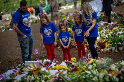 Jamie y Emma y sus hijas miraban el lunes las flores y mensajes colocados para la reina Isabel II en el memorial de Green Park, junto al palacio de Buckingham en Londres.