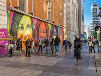 Personas con mascarilla pasean por la Gran Vía de Madrid junto al mural Nosotras Juntas que homenajea a activistas del feminismo. Getty Images