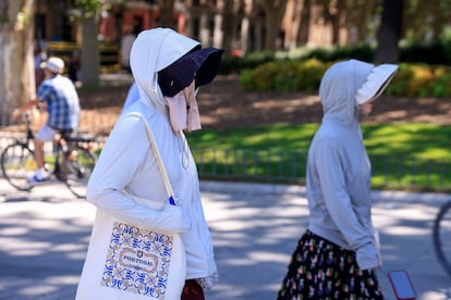 Dos turistas se protegen del sol en los alrededores del Palacio Real, este martes en Madrid.
