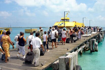 Un grupo de turistas hace cola para tomar el barco que las desalojará de Isla Muejeres ante la llegada de <i>Emily.</i>