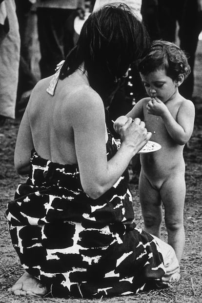 Una mujer con un maxivestido floral da de comer a su hija en Woodstock.