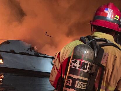 Um bombeiro trata de extinguir o incêndio declarado nesta segunda-feira em um barco em Califórnia.