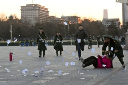 La policía china impide el paso a una mujer que intentaba protestar durante el izado de la bandera en la plaza de Tiananmen.