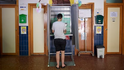Un joven coge la papeleta para votar en un colegio público de Granada.