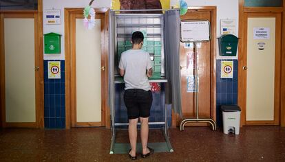 Un joven coge la papeleta para votar en un colegio público de Granada.