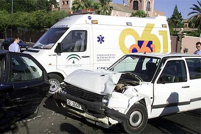 Una ambulancia, junto a dos coches accidentados en una avenida de Sevilla.