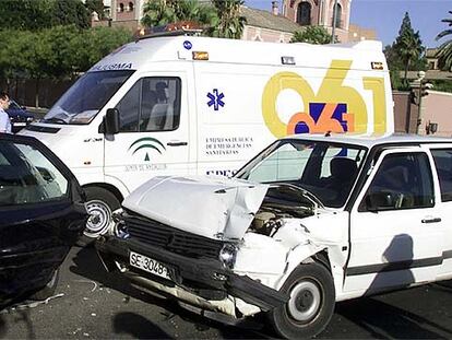 Una ambulancia, junto a dos coches accidentados en una avenida de Sevilla.