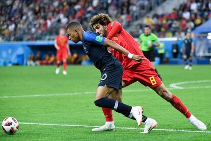 El jugador belga Marouane Fellaini lucha con Kylian Mbappe.