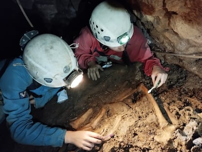 Dos arquelogos examinan restos de la Edad de Hierro encontrados en el interior de la sima La Cerrosa-Laga?a.