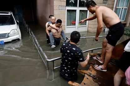 Varias personas ayudan a un anciano en una zona inundada en Zhuozhou, el jueves.
