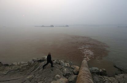 Un hombre camina junto a una tubería que descarga aguas residuales en el río Yangtze, provincia de Anhui (China).