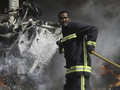 Un bombero trata de apagar el fuego dejado por la explosión.