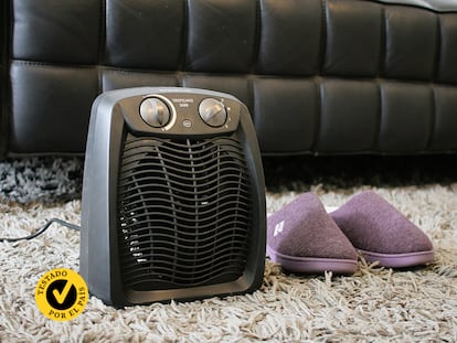 Un calefactor portátil con unas zapatillas en el salón de una casa.