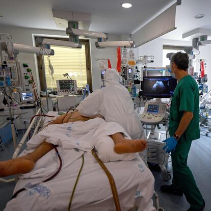 Healthcare workers in protective suits attend a COVID-19 patient at the Intensive Care Unit (ICU) of the Ramon y Cajal Hospital in Madrid on October 15, 2020. (Photo by OSCAR DEL POZO / AFP)