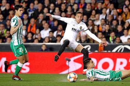 El delantero hispano brasileño del Valencia, Rodrigo, disputa un balón con los defensas del Real Betis, el francés Aísa Mandi, y Marc Bartra.