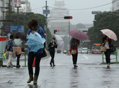 Peatones luchan para sostener sus paraguas mientras avanzan por las calles de Himeji, al sur de Japón. Las autoridades japonesas han activado los avisos de evacuación para más de 900.000 personas en 13 provincias afectadas.