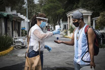 Una mujer voluntaria le coloca gel a un visitante al panteón de Xilotepec al sur de la Ciudad de México. Las autoridades han pedido a los mexicanos que eviten reunirse este año, y que la festividad se celebre en los domicilios de cada ciudadano. El subsecretario de Salud, Hugo López-Gatell, y la secretaria de Cultura, Alejandra Frausto Guerrero, comparecieron este jueves para pedir a los mexicanos que limiten la fiesta a la esfera familiar y hogareña.