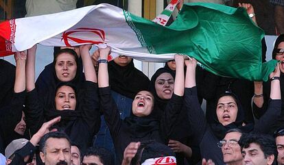 Varias mujeres ondean banderas de Ir&aacute;n en las gradas del estadio Azad&iacute; de Teher&aacute;n, durante un partido de clasificaci&oacute;n para el Mundial de F&uacute;tbol de Alemania 2006.