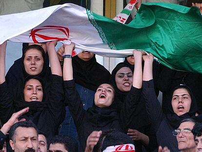 Varias mujeres ondean banderas de Ir&aacute;n en las gradas del estadio Azad&iacute; de Teher&aacute;n, durante un partido de clasificaci&oacute;n para el Mundial de F&uacute;tbol de Alemania 2006.